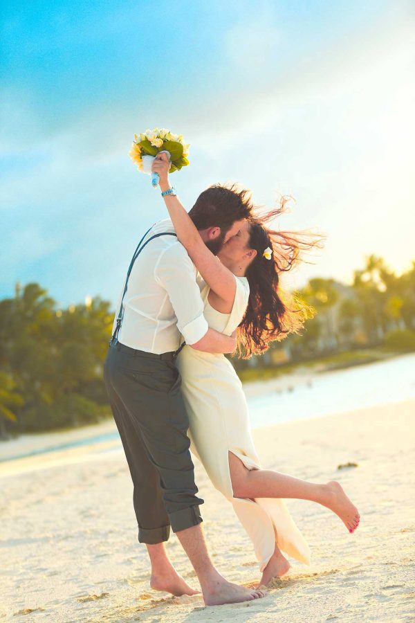 Couple kissing at the beach for a post wedding photoshoot 