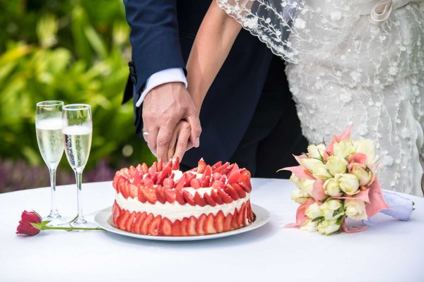 strawberry wedding cake cutting with champagne and beautiful bouquet