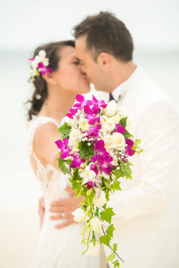 bride holding bouquet to kiss husband