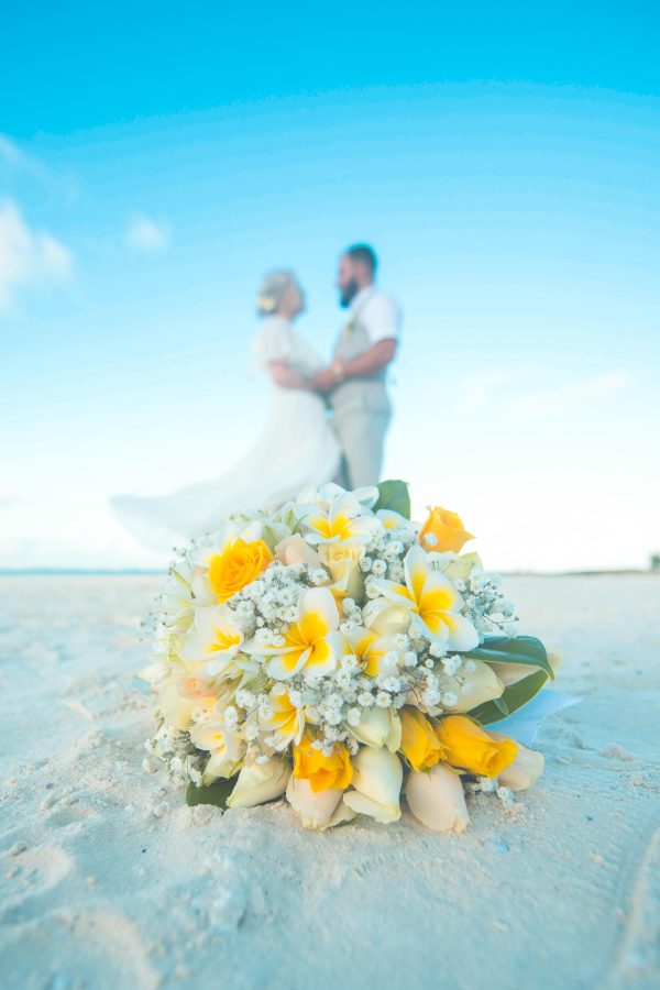 couple standing in background of yellow bouquet on the beach