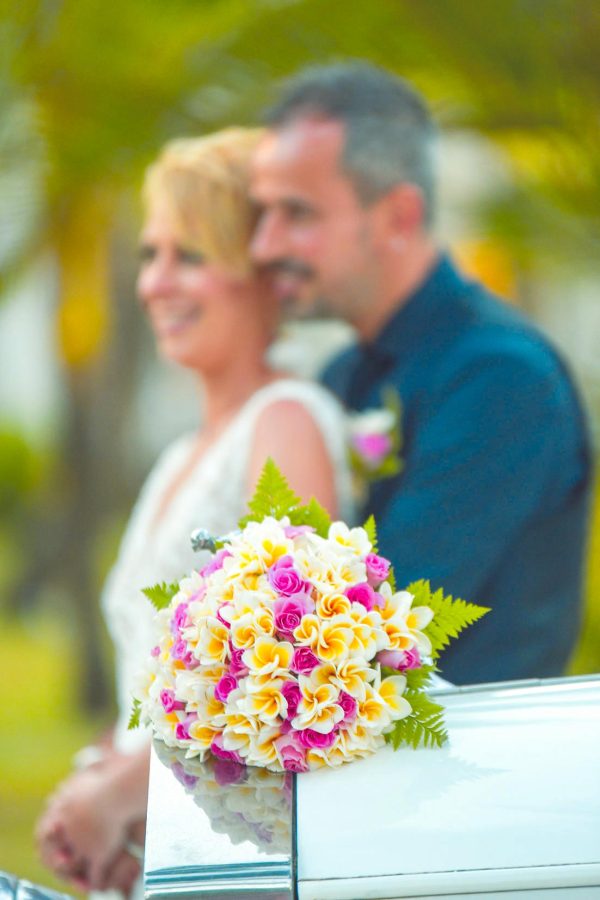 couple posing at the back of floral bouquet