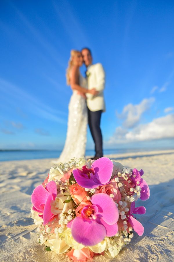 couple posing at the back of bouquet on beautiful beach