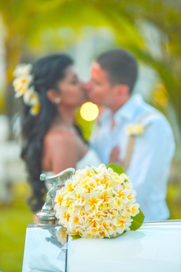 groom and bride kissing at the back of yellow bouquet