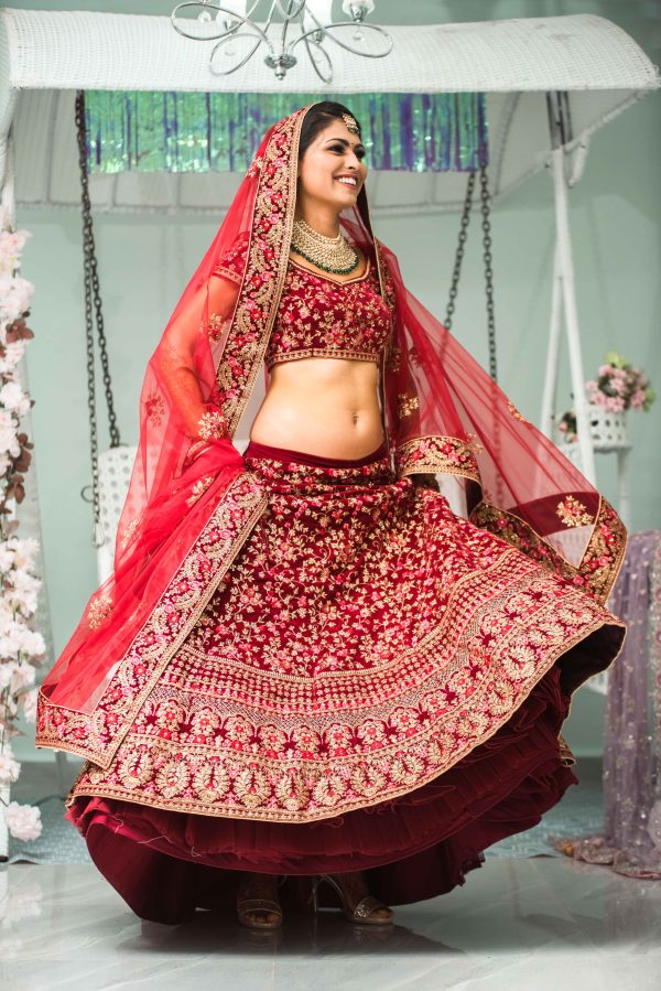 A bride is swirling around in her red saree 