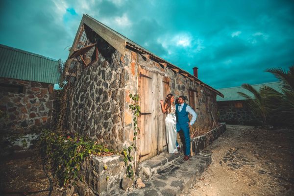 A couple is posing against a vintage house 