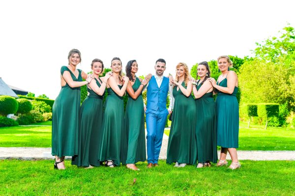 Groom posing with bridesmaids in nature 